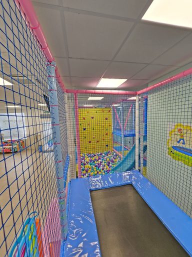 Zona de juegos con trampolín, paredes escalables y redes de seguridad.