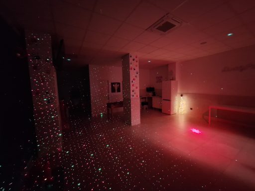 Sala oscura con luces láser rojas y verdes proyectadas en las paredes y el suelo.