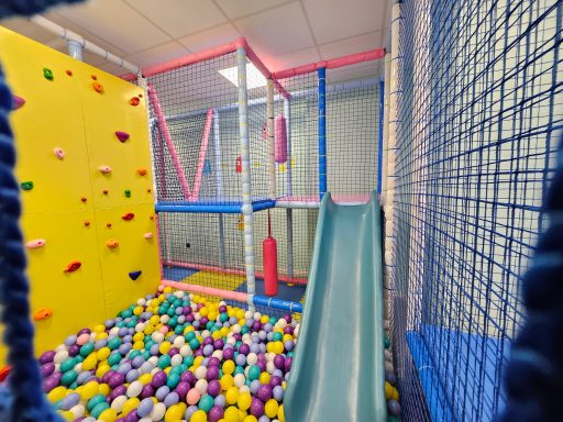 Zona de juegos con tobogán, pared de escalada y bola de plástico de varios colores.